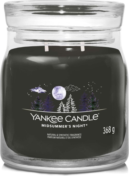 Een zwart geurkaars in een glazen pot met witte en paarse bomen, maan en sterren, gelabeld 'Yankee Candle Midsummer's Night' en gewicht.