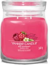 Een roze geurkaars in een glazen pot met een frambozen afbeelding en 'Yankee Candle' label.