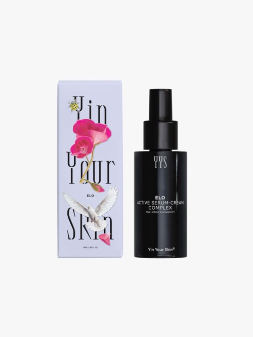 Mustavalkoinen suihkepullo YUS Elo Active Serum Cream ja violettiin, pinkkiin ja valkoiseen laatikkoon, jossa kukkia ja lintu.