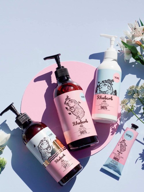 Vier Hautpflegeprodukte mit Pandabild, pinken und weißen Etiketten und Blumen auf hellem Hintergrund.