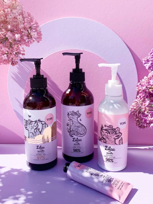 Drei Pumpflaschen mit Tierillustrationen, eine Tube, Blumen und rosa Hintergrund. Die Flaschen haben Etiketten und Pumpköpfe.