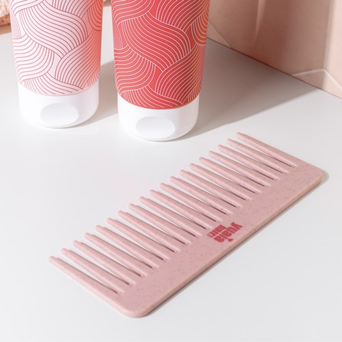 Kaksi pulloa ja vaaleanpunainen harja ovat valkoisella pinnalla, pulloissa on yhteensopiva pinkki design ja pinkki logo.