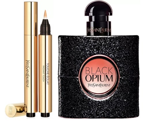 Een parfumfles met 'Black Opium' van Yves Saint Laurent, met twee gouden make-up potloden ernaast.