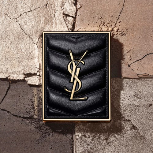 A YSL necklace in a black box, placed on a cracked stone surface.