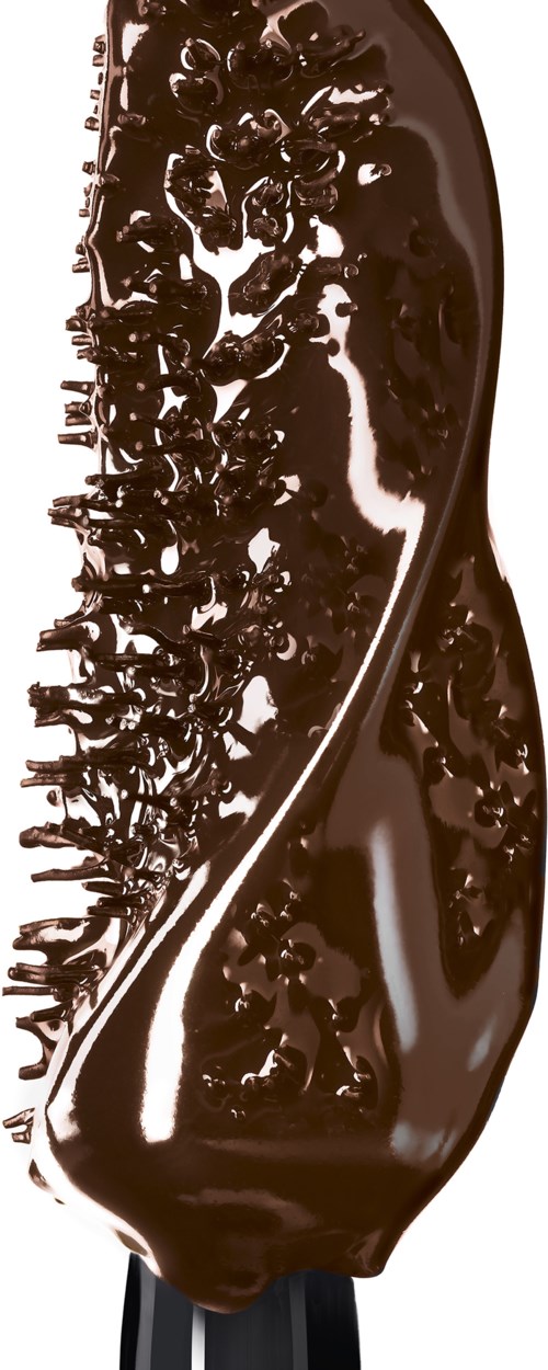 A spoon covered with melted chocolate and chocolate sprinkles. The spoon holds a lot of glossy chocolate.