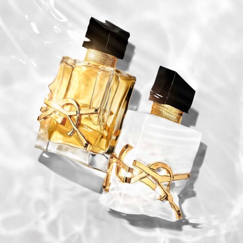 Twee parfumflesjes met zwarte doppen en gouden kettingen gevormd als een logo, geplaatst op een lichte ondergrond.