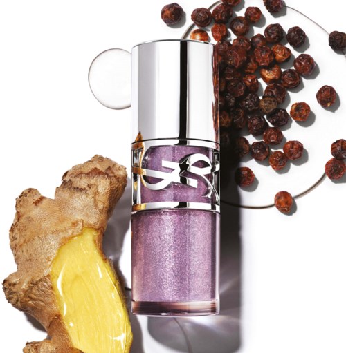 Lip gloss with purple shimmer, ginger root, and dried red peppercorns on a white background.