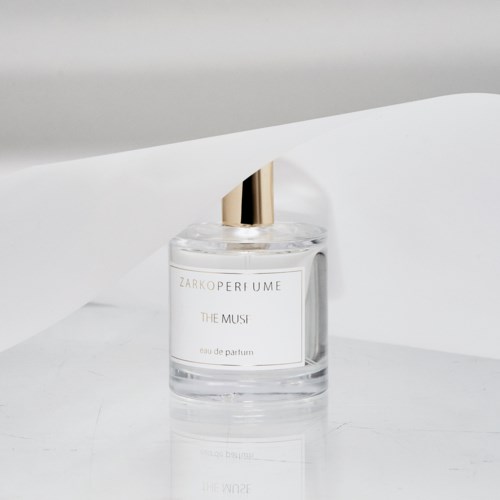 Näkyvä hajustepullon kulttinäytöllä ja kullansävyisellä suuttimella, teksti 'ZARKO PERFUME THE MUSI'.