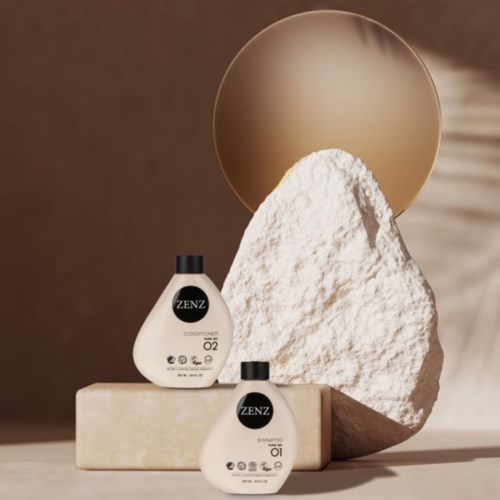 Two white bottles labeled ZENZ, placed on a beige block, with a large white stone and a round gold mirror behind.