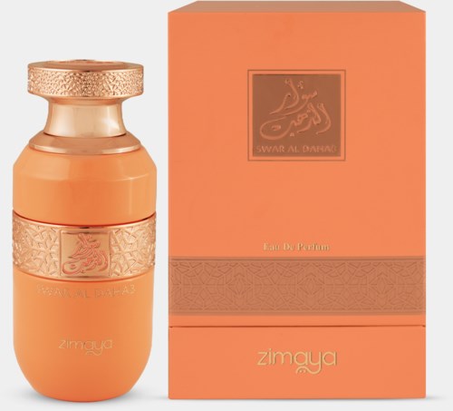 Een parfumfles met een gouden dop en een perzikkleurige doos met gouden details en Arabische tekst.