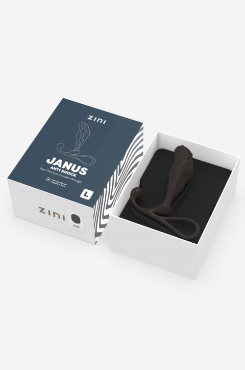 Eine Box enthält ein schwarzes, gebogenes Objekt, gekennzeichnet Janus, mit einfachem Design und Verpackung.