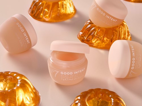 Small jars of pink cream surrounded by shiny, orange, jelly-like ornaments. The jars are labeled GOOD INTENT.