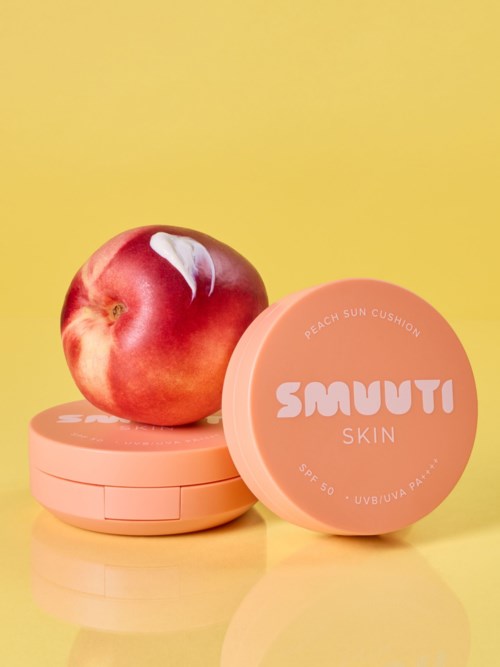 En persika vilar på en rosa behållare märkt Smuuti Skin, med en annan behållare bredvid, mot en gul bakgrund.