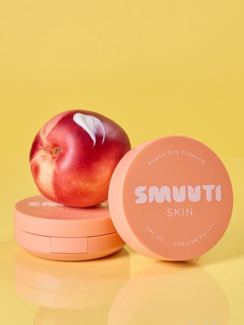 En persika vilar på en rosa behållare märkt Smuuti Skin, med en annan behållare bredvid, mot en gul bakgrund.