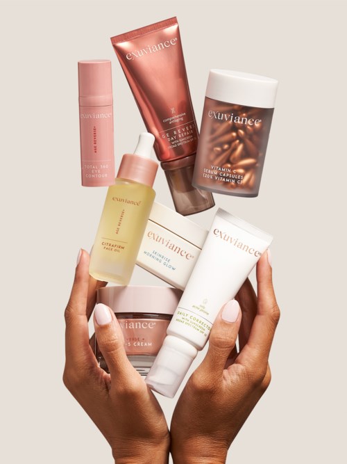 Hender holder ulike hudpleieprodukter, inkludert kremer og serum, i ulike flasker og tuber, pent arrangert.