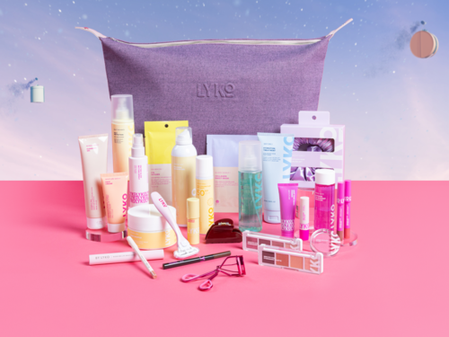Olika hudvårds- och makeupprodukter arrangerade framför en lila Lyko-väska på en rosa och blå bakgrund.