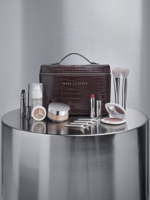 Makeup-kit med borstar, läppstift, rouge och hudvårdsprodukter på ett silverbord.