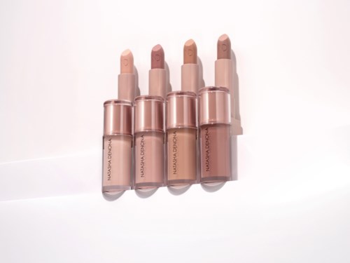 Fyra beige och rosa läppstift i genomskinliga hylsor, placerade i rad på en vit bakgrund.