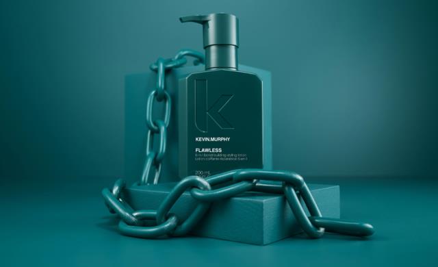 En mörk turkos tvålpumpflaska märkt Kevin Murphy Flawless, omgiven av en tjock kedja, på en liten plattform.