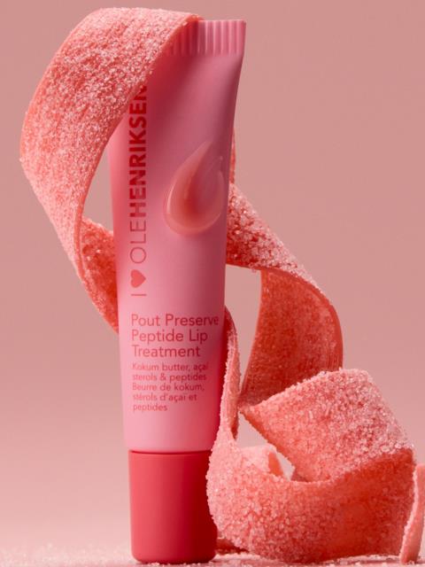Läppvårdsrör i rosa med peel-ingredienser, omgiven av rosa peelstrimlor på rosa bakgrund.