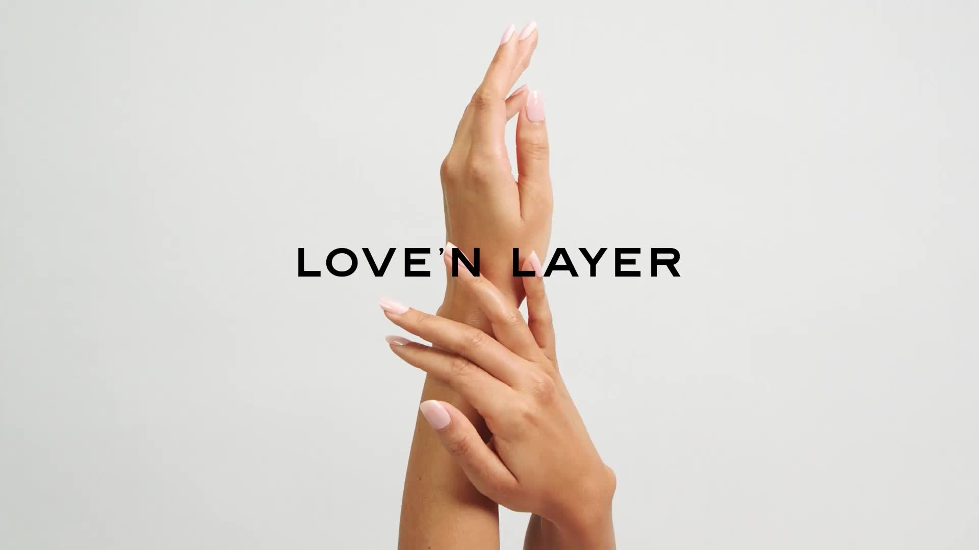 Två händer berör varandra med fingrar sammanflätade, ovanför orden "Love'n Layer" på vit bakgrund.